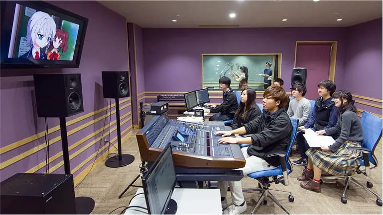 モニターの映像を見る学生たちと奥の部屋でアフレコ作業をしている学生の様子