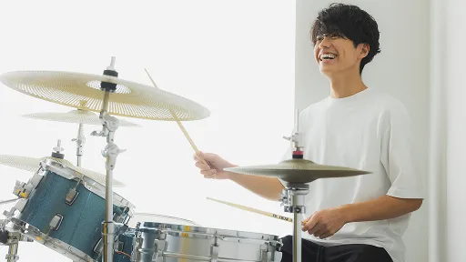 学生が笑顔でドラムのレッスンをする様子