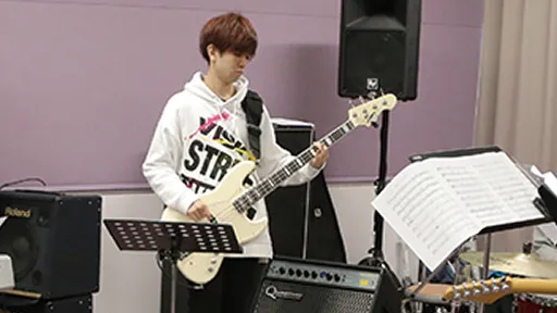 学生が楽譜を見ながらベースのレッスンをする様子