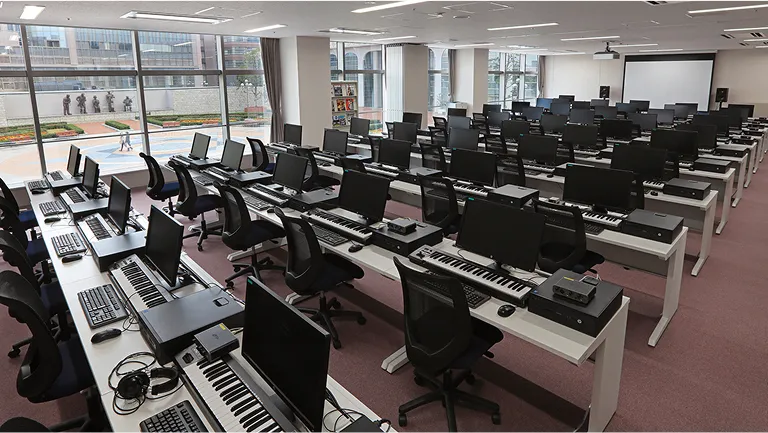パソコン、キーボード、ヘッドホンなどの機材が完備された音楽実習室