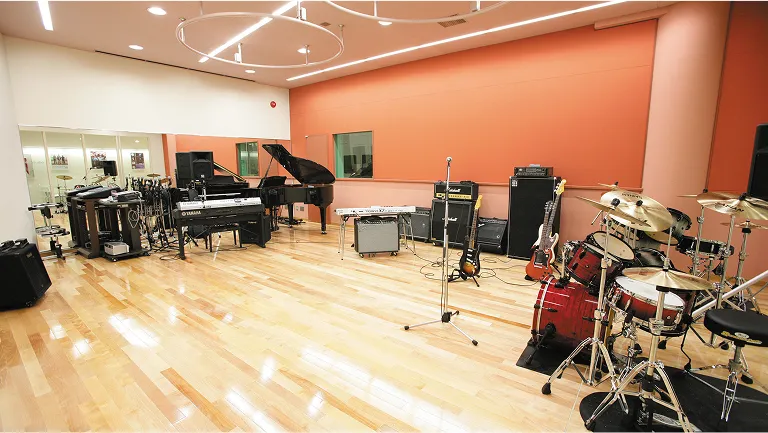 広い空間と木製の床が特徴で、複数の楽器が設置されたスタジオ