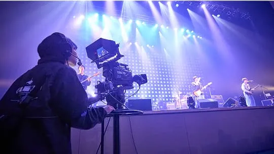 ステージ上で歌っている人を撮影している学生