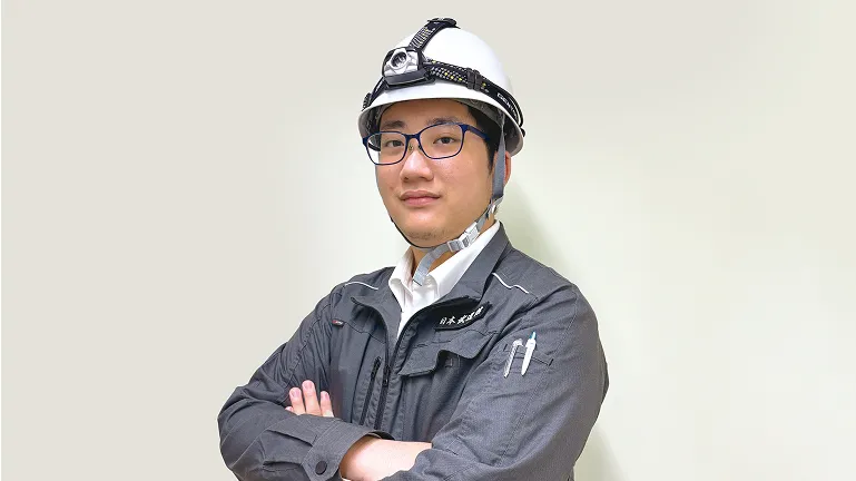 作業着を着用し腕を組んでいる川辺 優輝彦さん