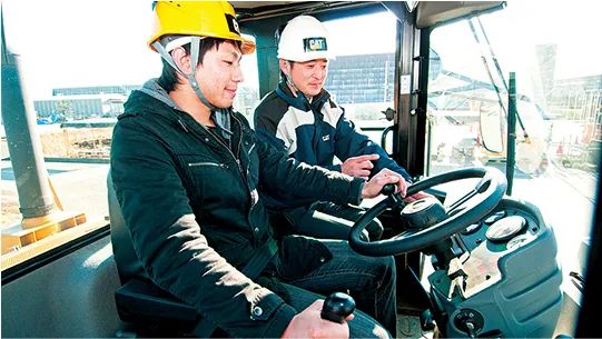 学生が講師に教わりながら建設機械を運転している様子