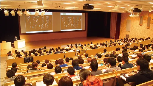 大勢の学生たちがステージに設置されているスクリーンを見ながら話を聞いている様子