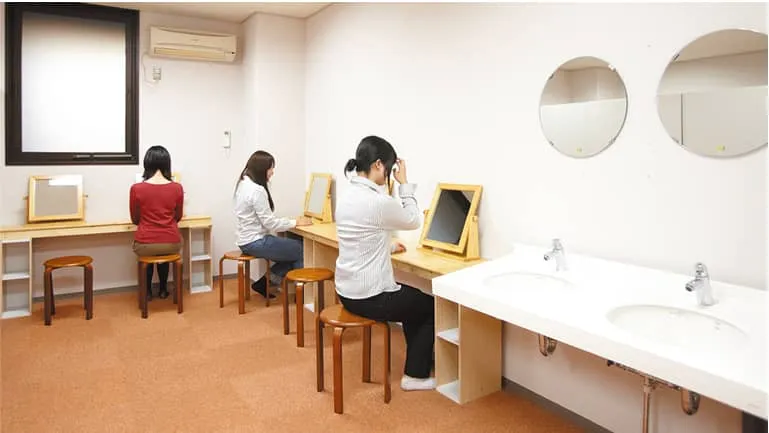 学生たちがパウダールームで身だしなみを整える様子