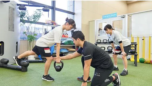 ケトルベルでトレーニングする生徒と補助をするコーチ