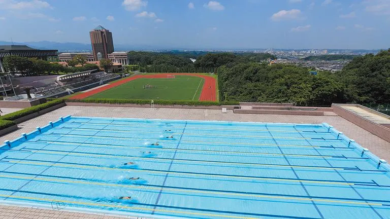 後方に総合グラウンドが見える、広くて清潔な屋外プール