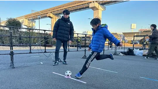 子供がサッカーボールを蹴るのを見守る生徒