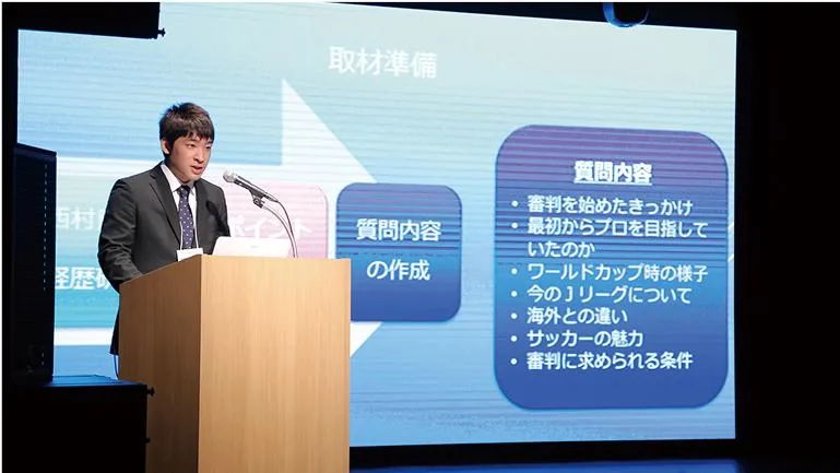 スーツ姿で壇上に上がり、プロジェクターで資料を映しながらプレゼンをする生徒