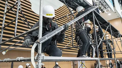 学生たちがヘルメットを着用し安全帯を使用しながらセットを組み立てている様子