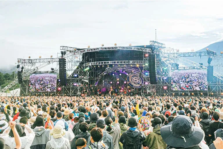 大勢の観客が野外ライブステージに集まる様子