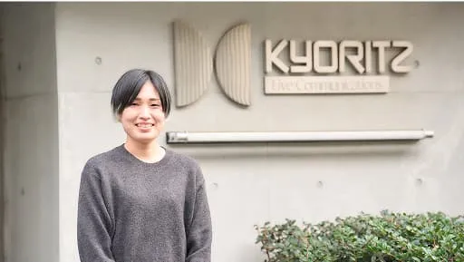 社名看板の前で話す綿貫 有里恵さん