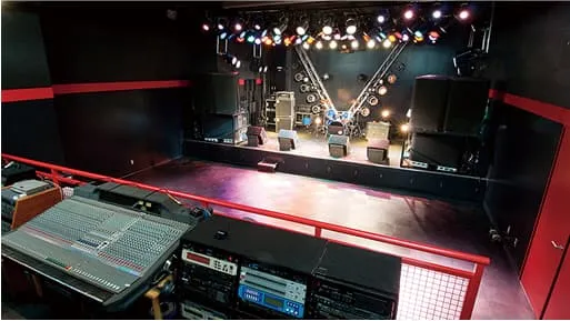 音響調整卓と照明や楽器が設置されたステージ