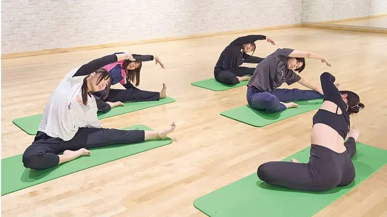 ヨガマットの上でストレッチをする講師と生徒たち