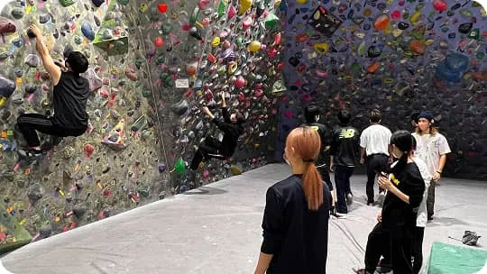 広い環境でボルダリングをする生徒たち