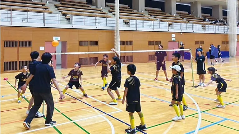 子供と一緒にバレーボールをする生徒たち