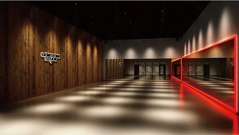 木目調の壁と鮮やかな赤色のライトで縁取られた鏡が印象的なダンススタジオ