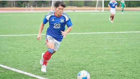 サッカーボールに向かって走る選手