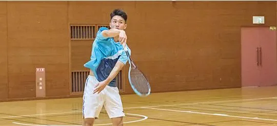屋内で学生がラケットを振り切っている様子