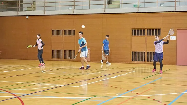 学生たちがアリーナでソフトテニスをしている様子
