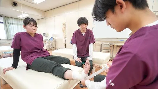 女性の足にテーピングをしている男性と、見守っている男性の様子