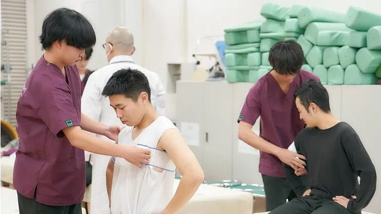 学生たちがベッドに腰を掛けている人のケアを行っている様子