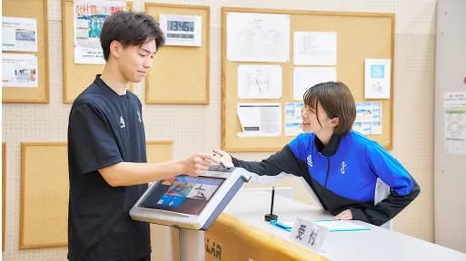 受付の女性が男性に案内をしている様子