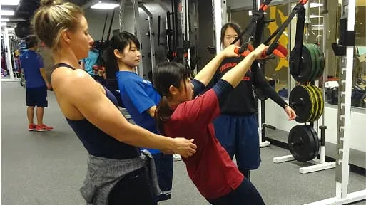 学生がサポートを受けながらトレーニングマシンを使用している様子