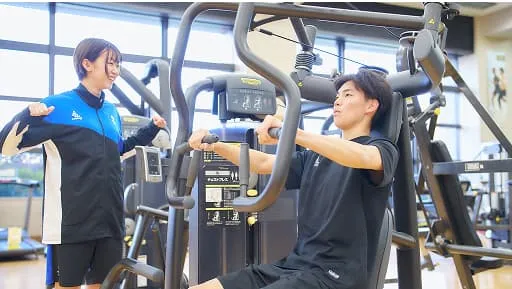 トレーニングマシンを使用している男性と指導している女性の様子