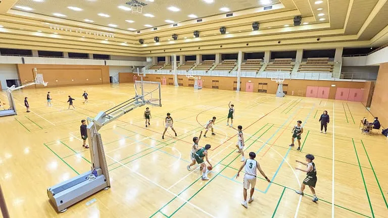 学生たちがアリーナでバスケットボールをしている様子