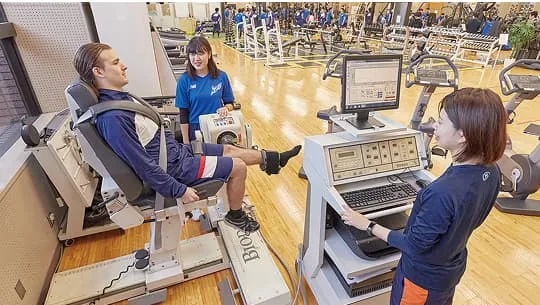 マシンに座っている男性の測定データを女性が解析している様子