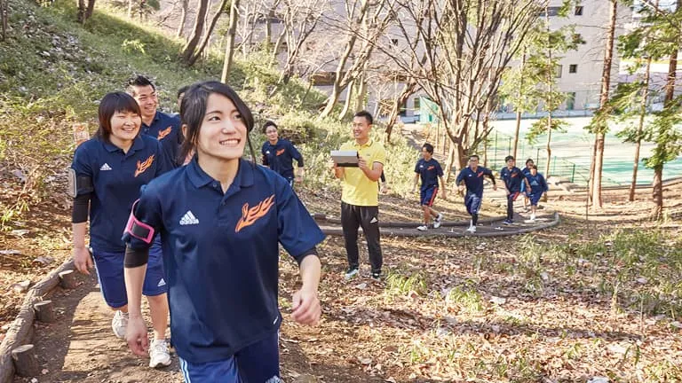 学生たちが自然に囲まれた学内のウォーキングエリアでウォーキングをしている様子