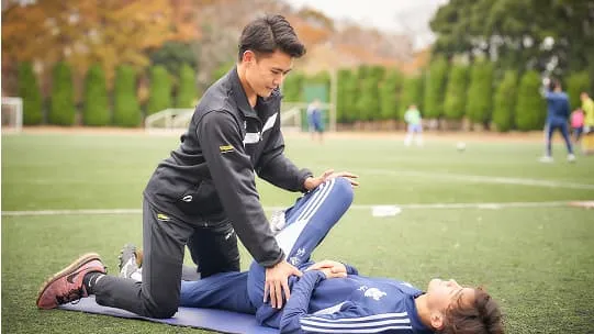 学生が横になっている選手のケアをしている様子