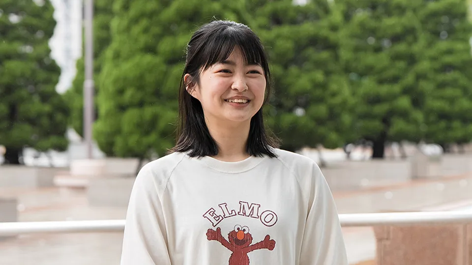 自然に囲まれた屋外で笑顔で話す坂本 琴美さん