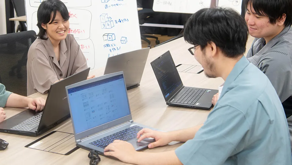 ノートパソコンを開いて会話をしている学生たち