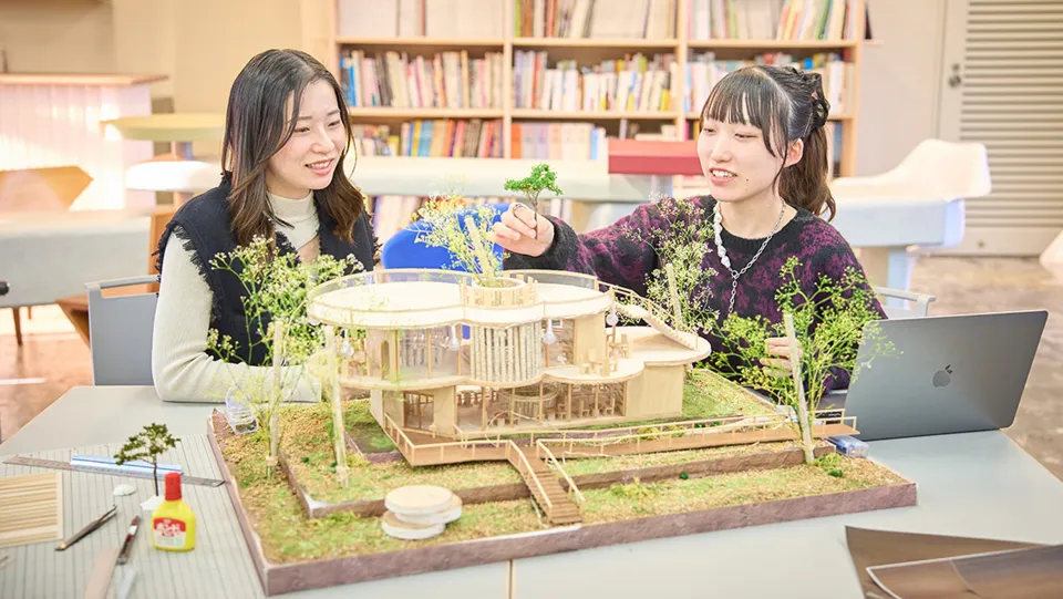 学生たちがテーブルに広げた紙とペンを囲んで話している様子