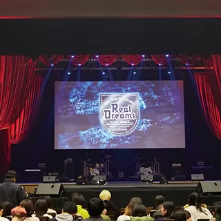 ステージ上の大型スクリーンに映像が投影されている画像