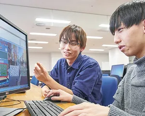 ゲームをしている画面と手元にプログラミング中の手元のイラスト