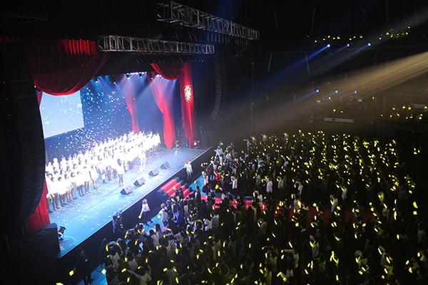 ステージ上でスポットライトと歓声を受ける学生達の風景