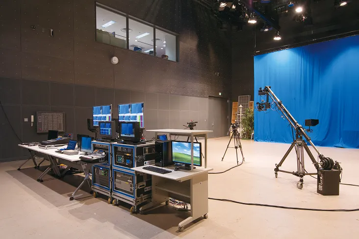 合成撮影用の幕が壁沿いに張られている、撮影機器とデスクが設置されたスタジオの様子