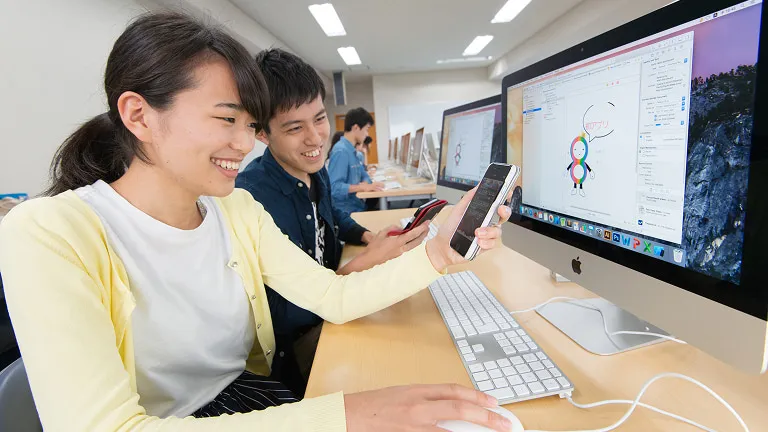 パソコンとスマートフォンを使って作業をしている学生