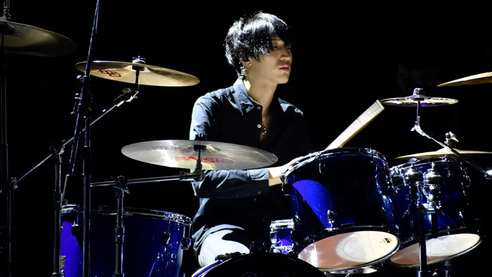 学生が照明に照らされたステージでライブパフォーマンスをする様子