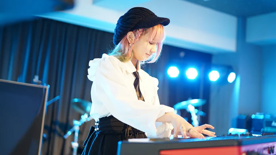 学生が照明に照らされたステージでライブパフォーマンスをする様子