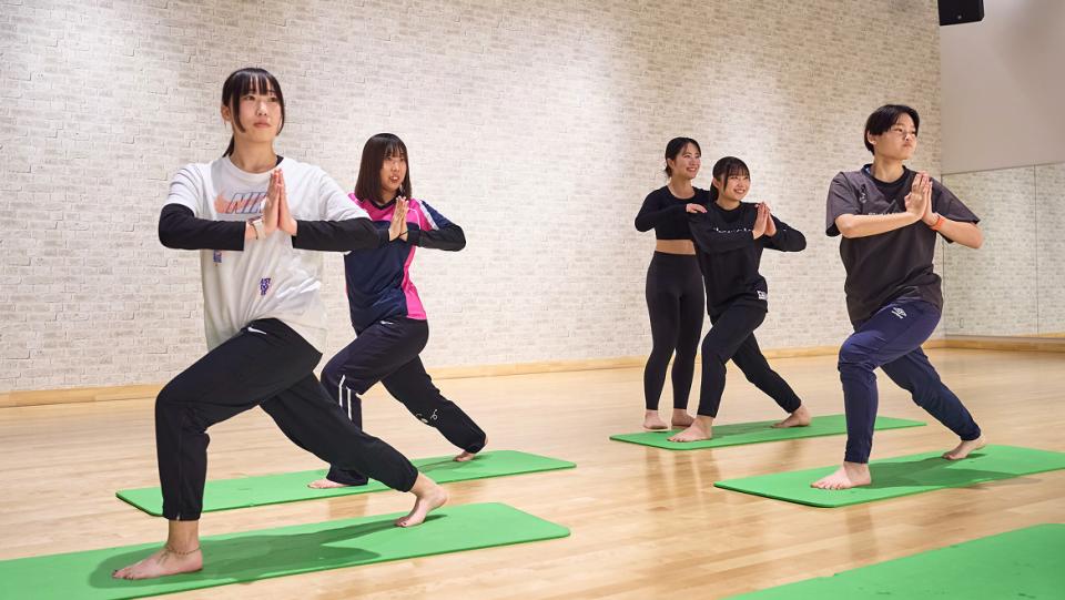 ヨガマットの上でストレッチをする講師と生徒たち