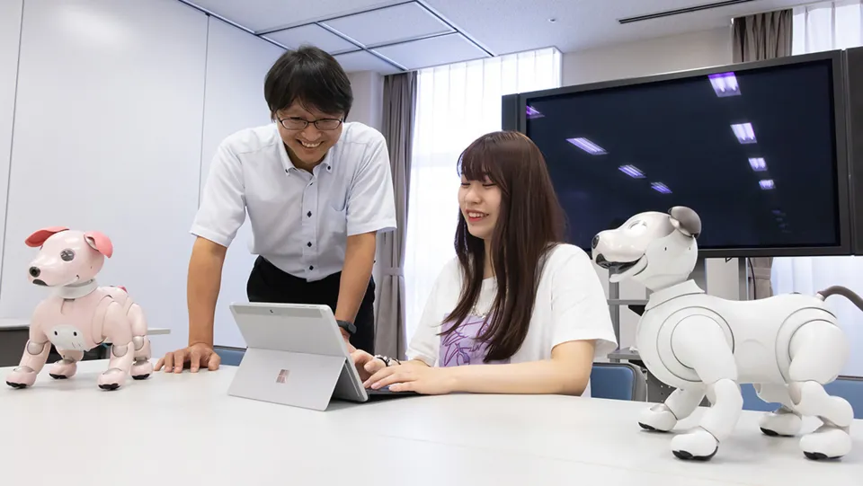 学生が組み立てたロボットを持って話す様子