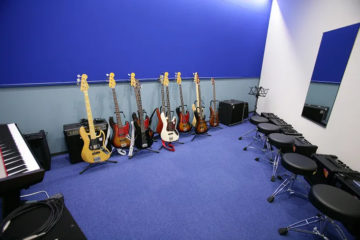 深い青を基調とした室内にたくさんのアンプやベースが並び、姿見サイズの鏡も壁に設置された集中できる空間