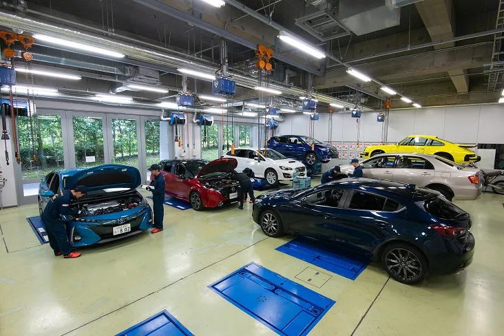 さまざまな車種が並んだ実習場で車両整備の授業を行う様子