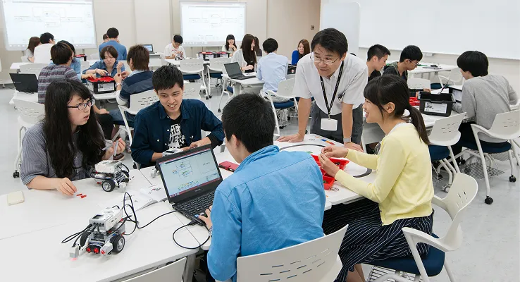 学生たちがロボットキットとパソコンを使い、グループで実習に取り組む様子