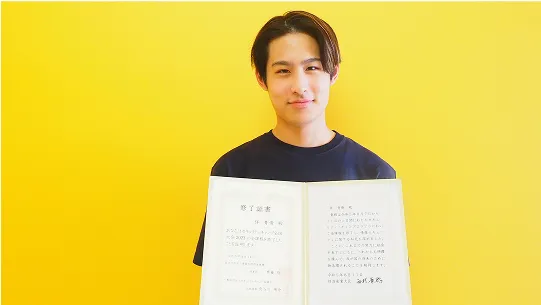 修了証を持った笑顔の学生